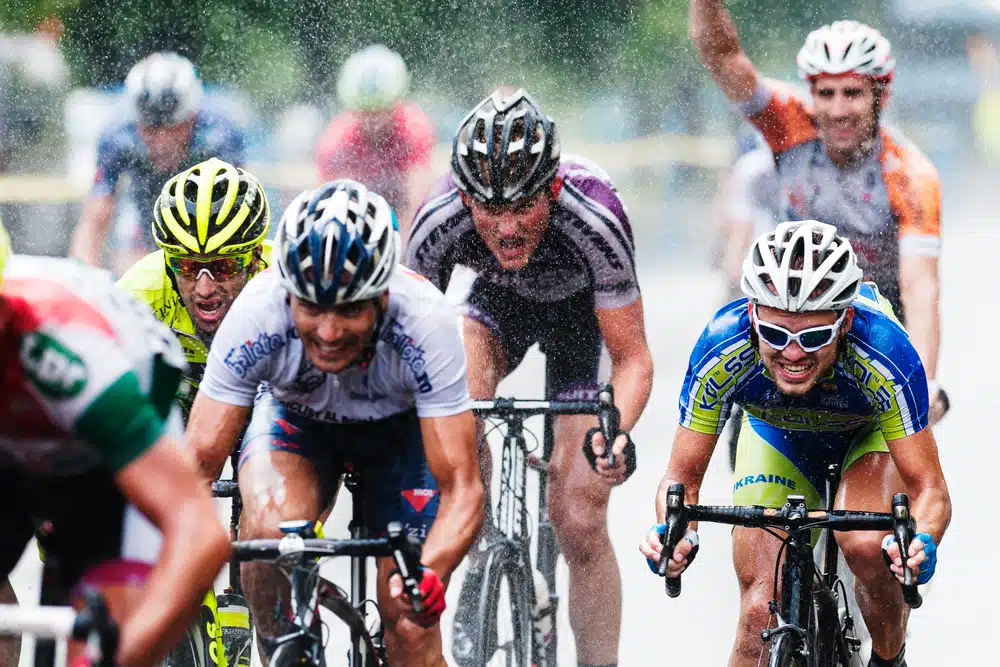 De fietsers racen in de regen en proberen maximaal te presteren.